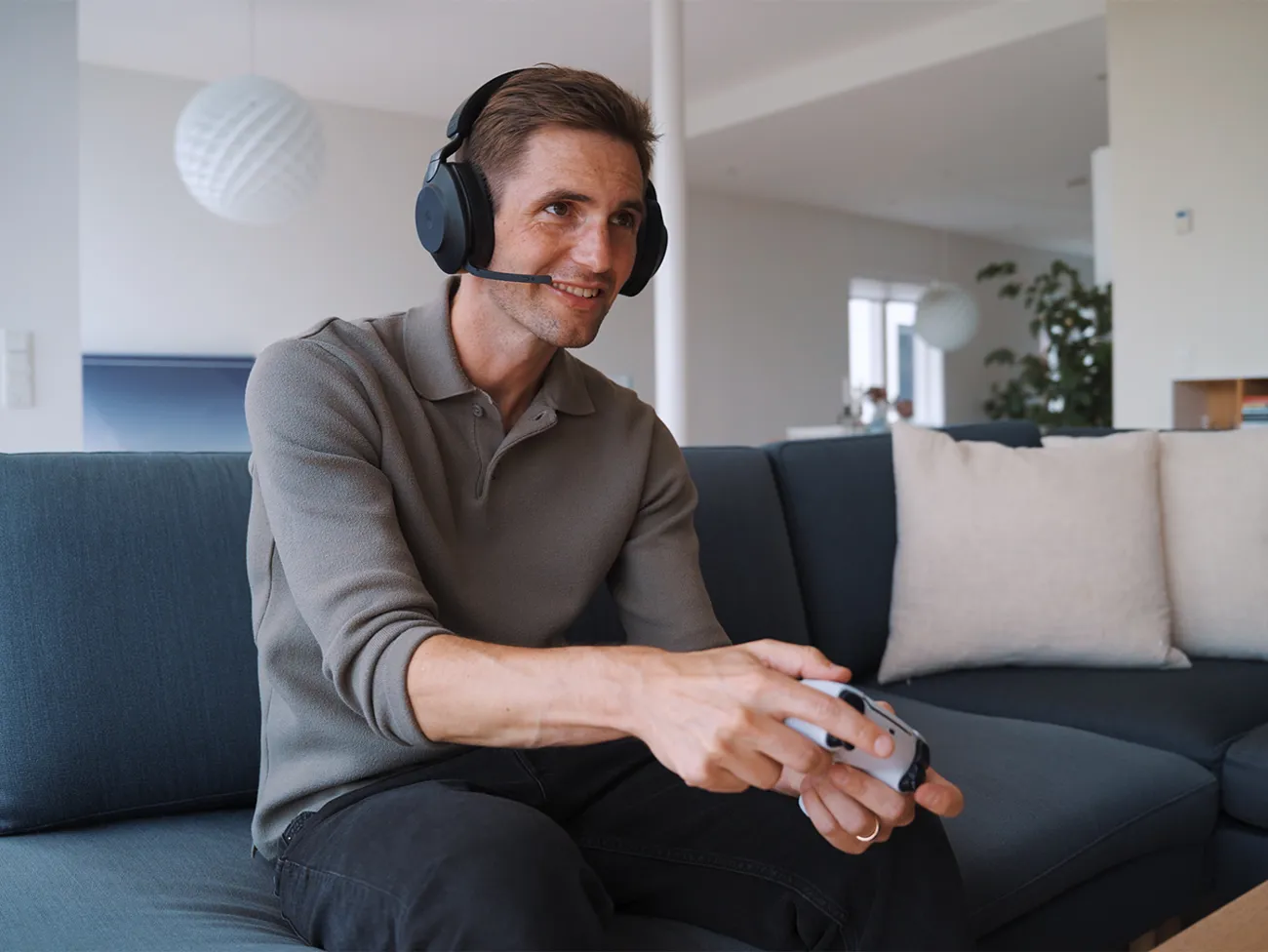 Mand sidder i sofa og online gamer med headset og gaming controller