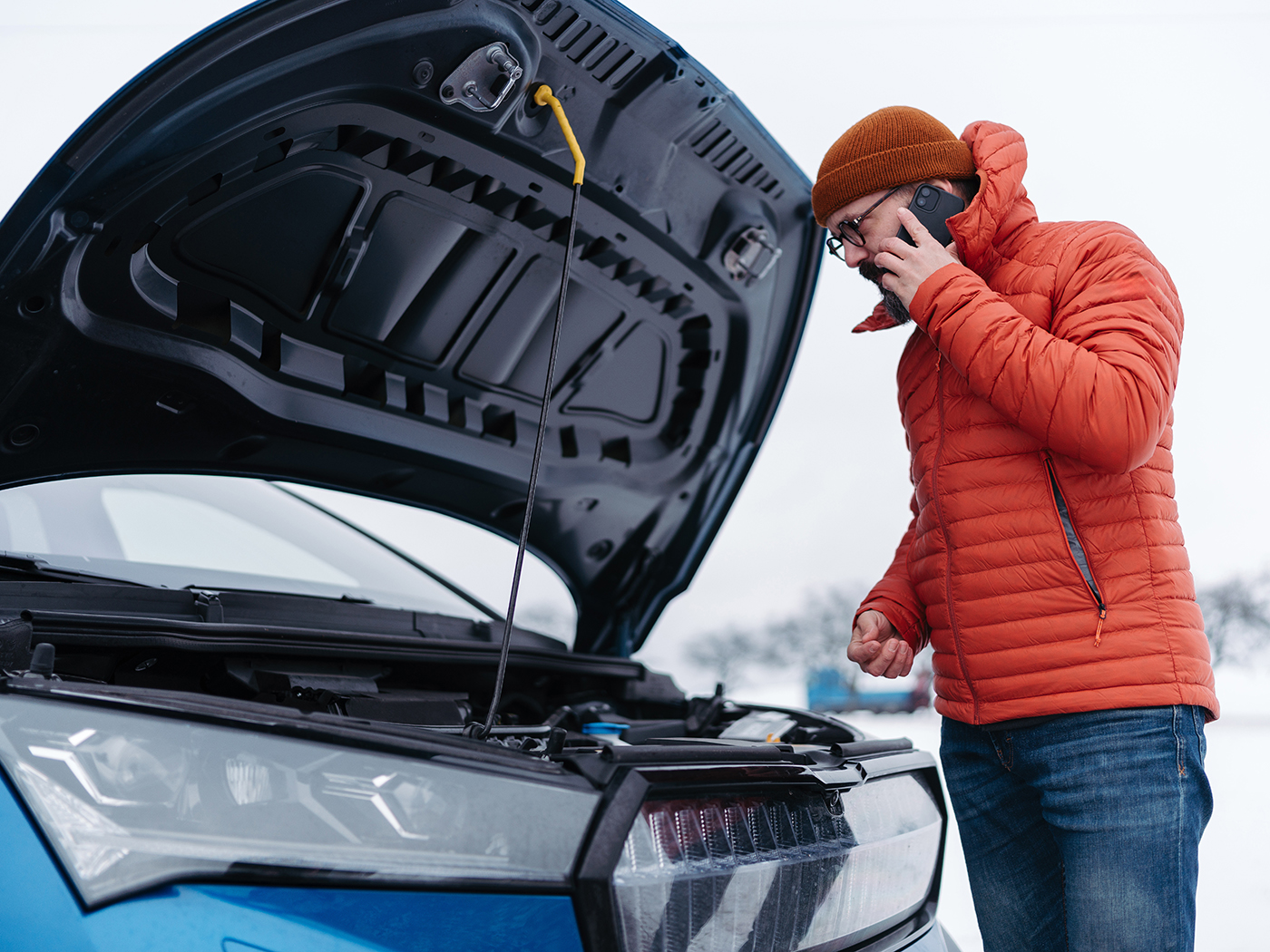 Mand ringer til vejhjælp med klappen åben til kølerhjelmen på hans elbil i vinterkulden