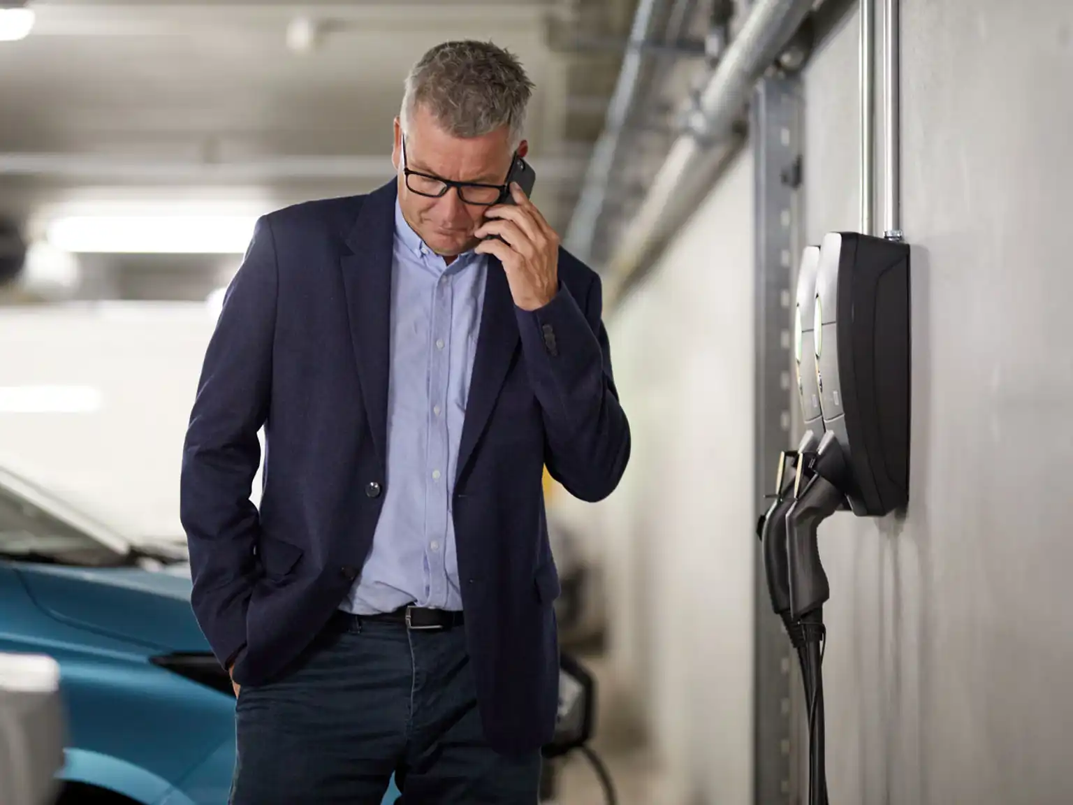 Mand taler i telefon ved siden af ladestander