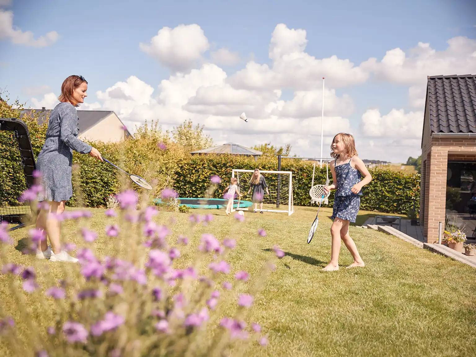 Kvinde og pige spiller badminton i haven