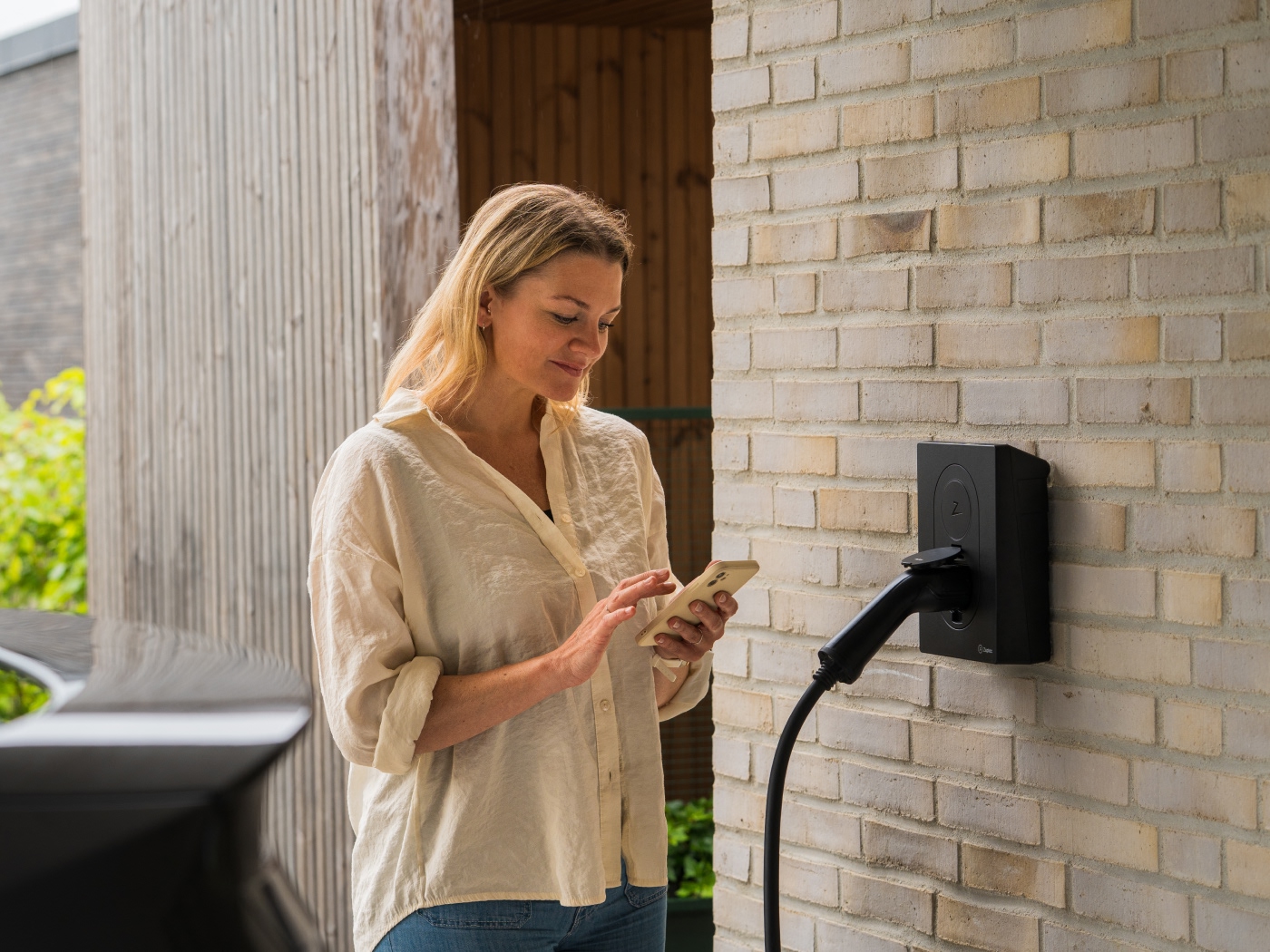 Kvinde ser på hendes telefon foran hendes ladeboks