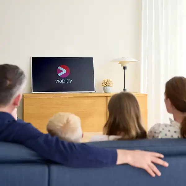 Familie sidder sammen i en sofa de streamer Viaplay på tvet