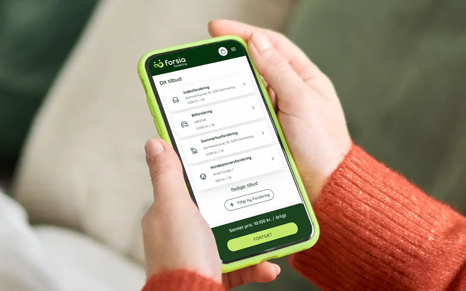 Person sidder i en sofa med sin mobiltelefon og ser på forsikringstilbud fra Forsia Forsikring