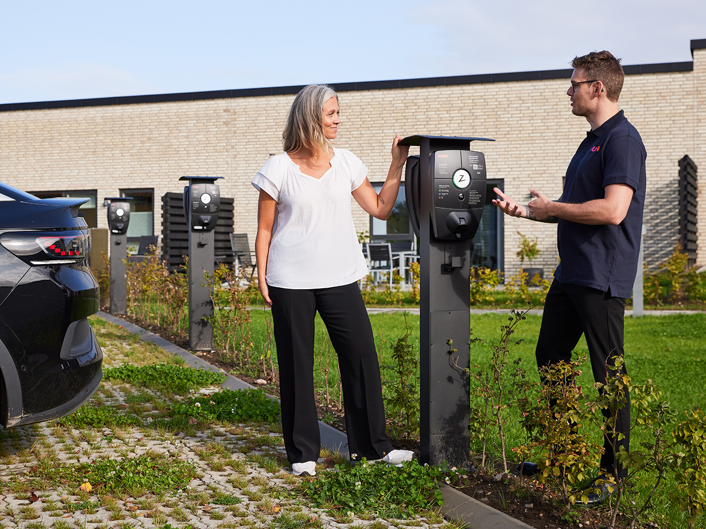 AURA-installatør står og taler med kunde ved ladestander i boligkvarter