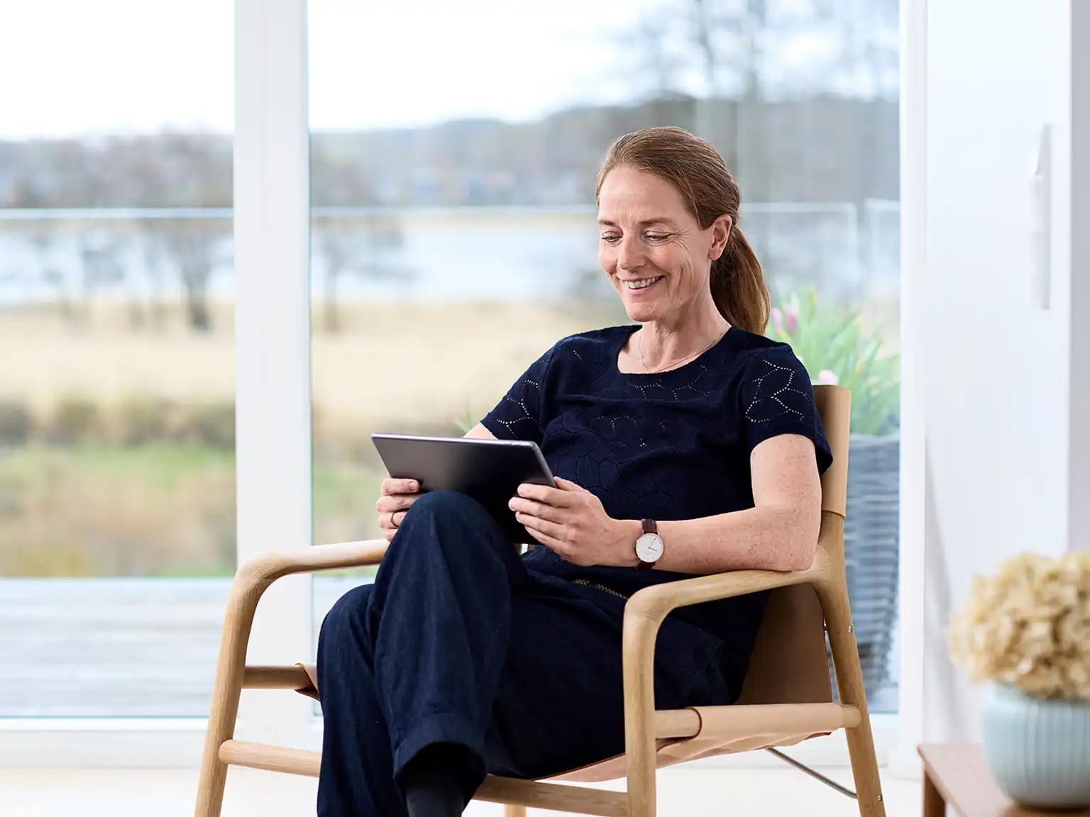 Kvinde sidder i stol med tablet