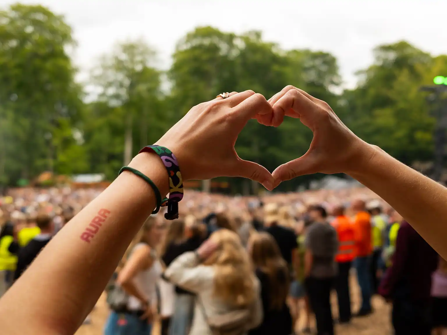 Hænder der former et hjerte på Smukfest med AURA tatovering på armen