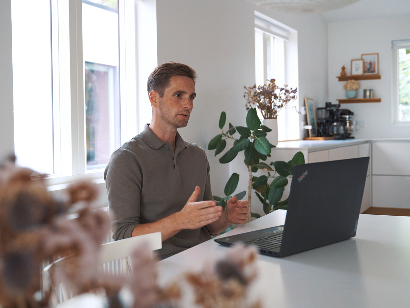 Mand sidder ved et bord i online videomøde med computer foran sig