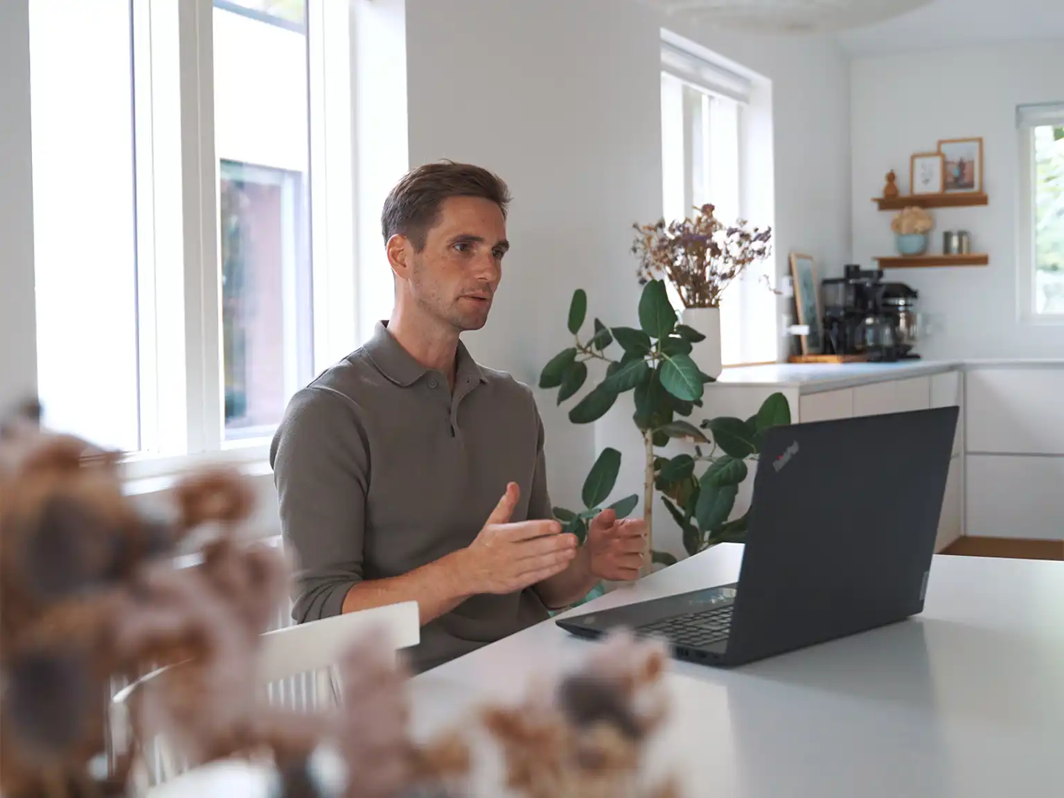 Mand sidder ved et bord i online videomøde med computer foran sig