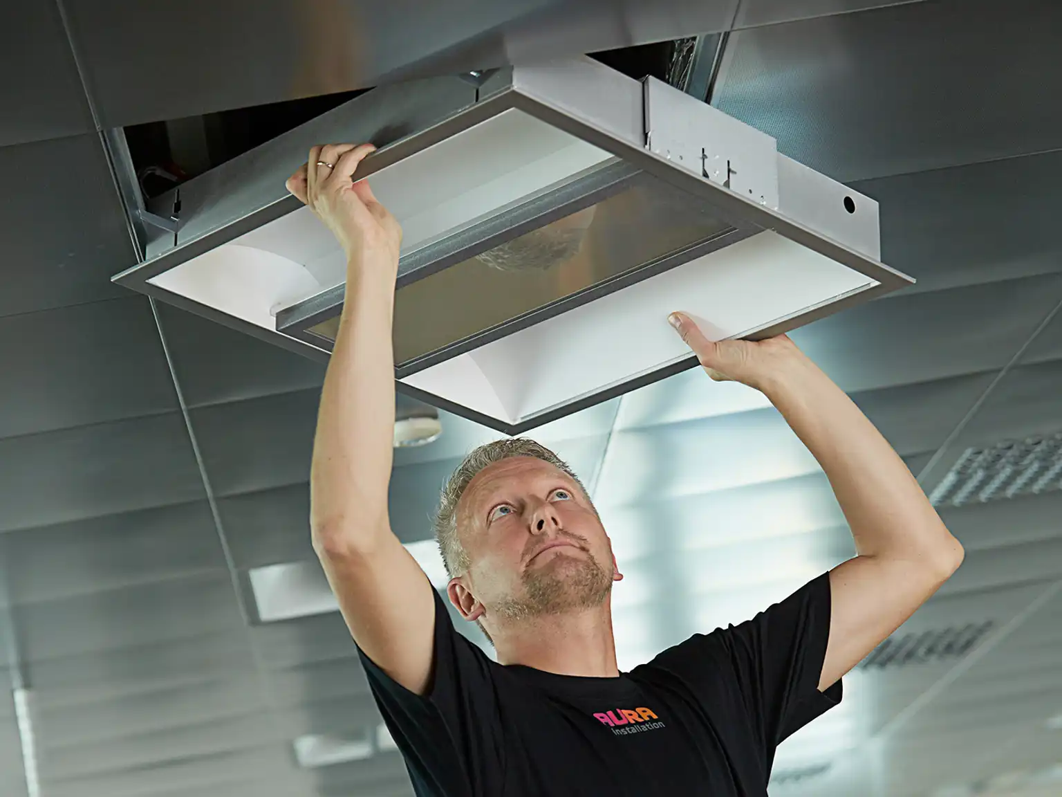 AURA installatør monterer led-belysning i loftet inde på kontor
