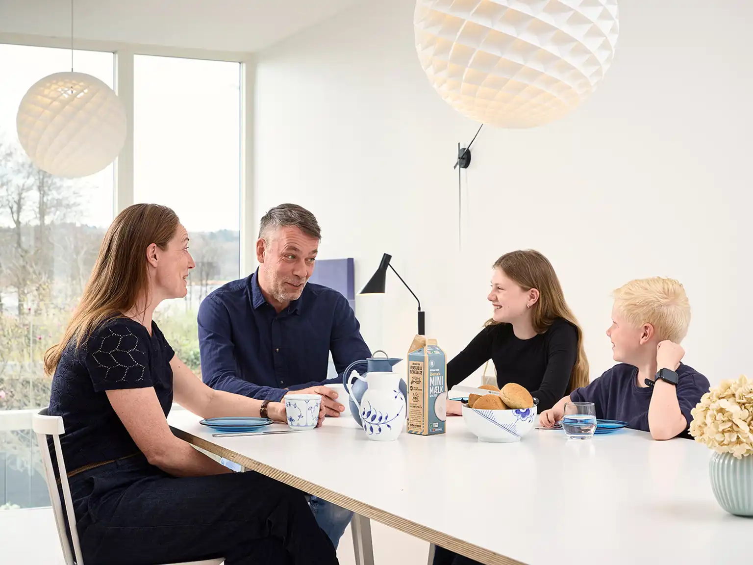 Familie sidder ved spisebordet og skal til at spise morgenmad