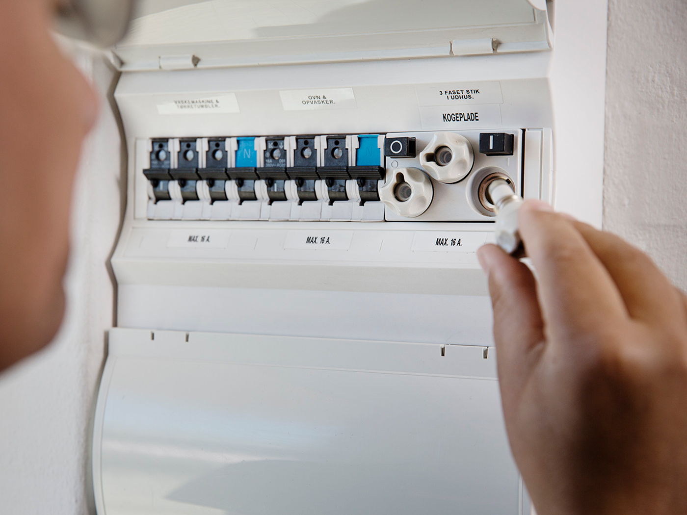 Mand sætter ny sikring i eltavle