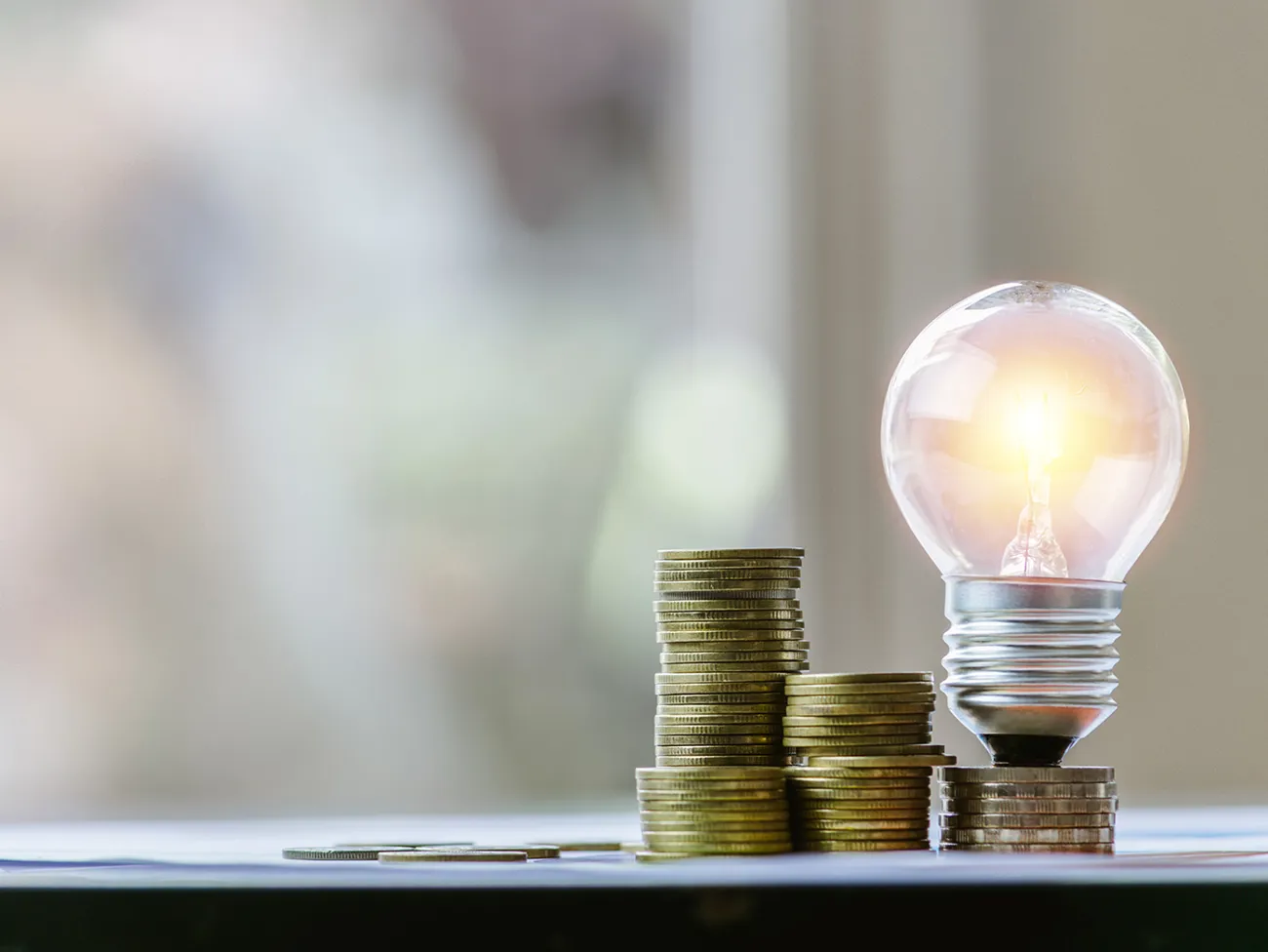 Stakke af mynter og en pære med lys i