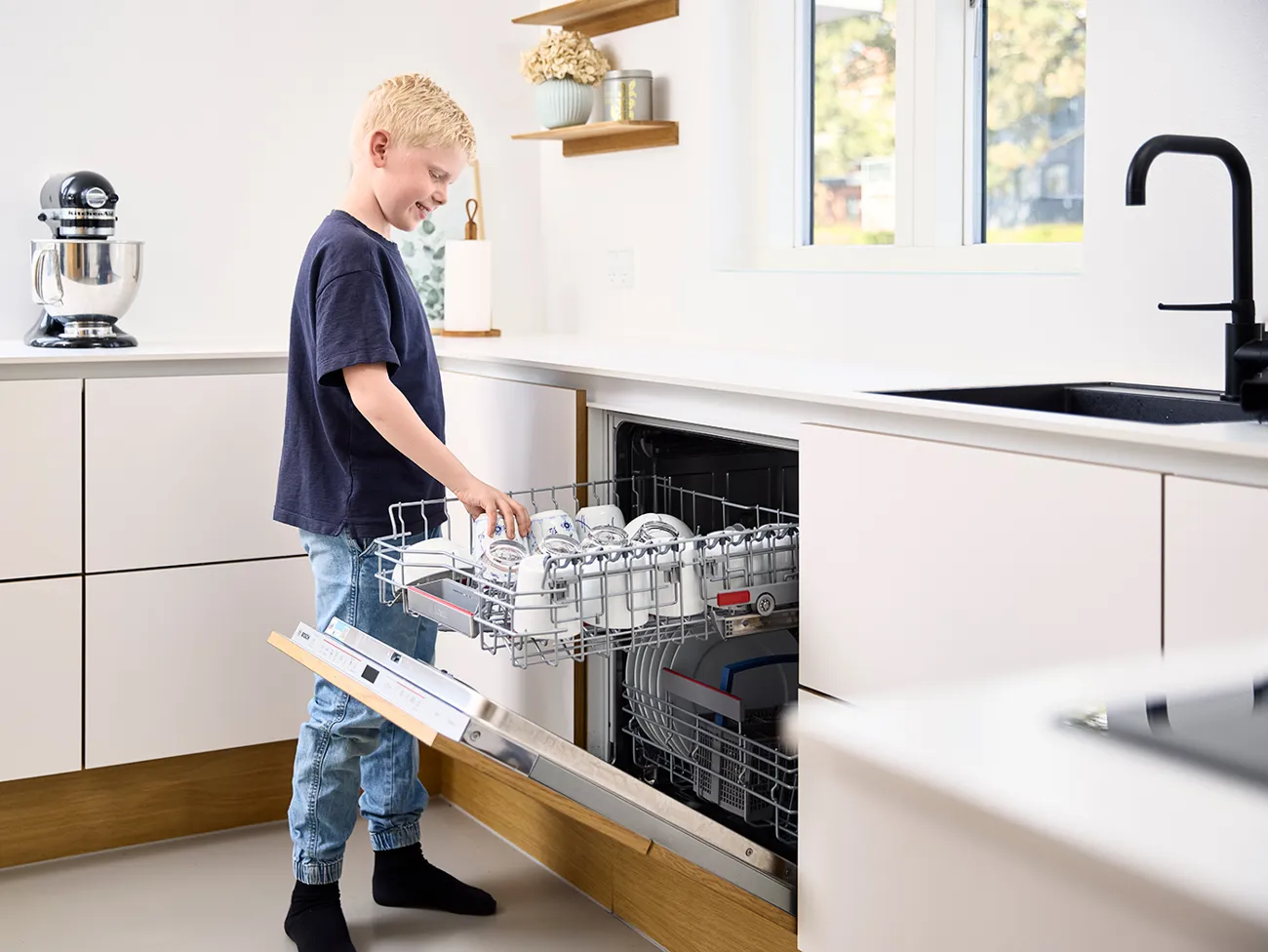 Dreng sætter kop i opvaskemaskinen
