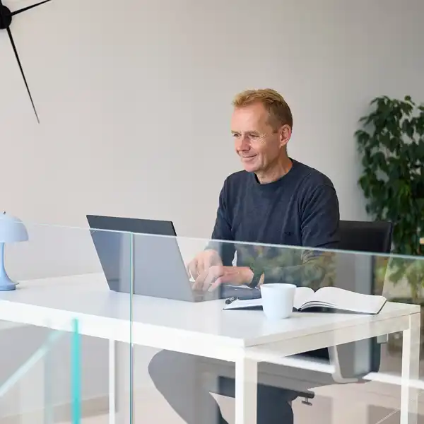 Mand sidder ved skrivebord og taster på sin computer