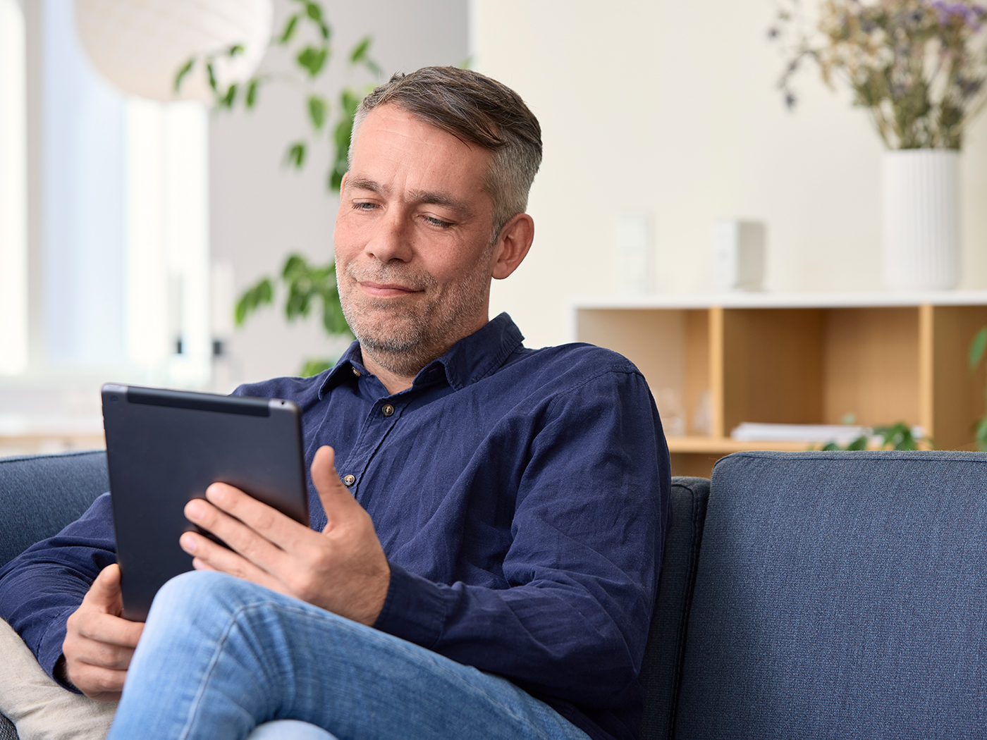 Mand slapper af i sofaen med sin tablet