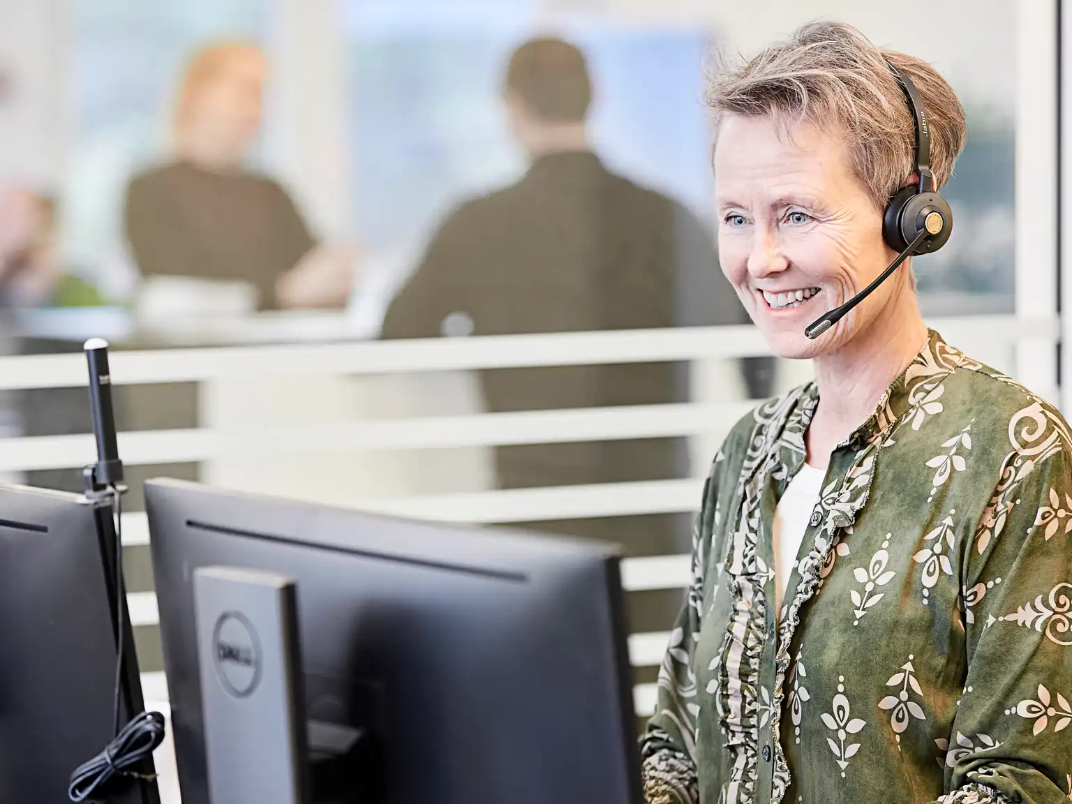 Kvinde står ved sin pc med høretelefoner på