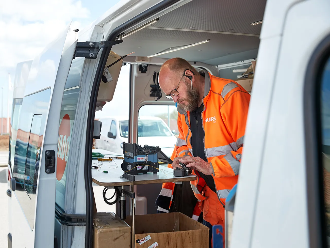 Fibertekniker står og laver teknisk arbejde i en teknikker bil fra AURA