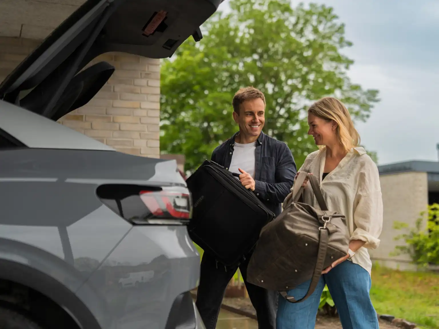 mand-og-kvinde-pakker-bilen Mand og kvinde pakker deres tasker i bilens bagagerum
