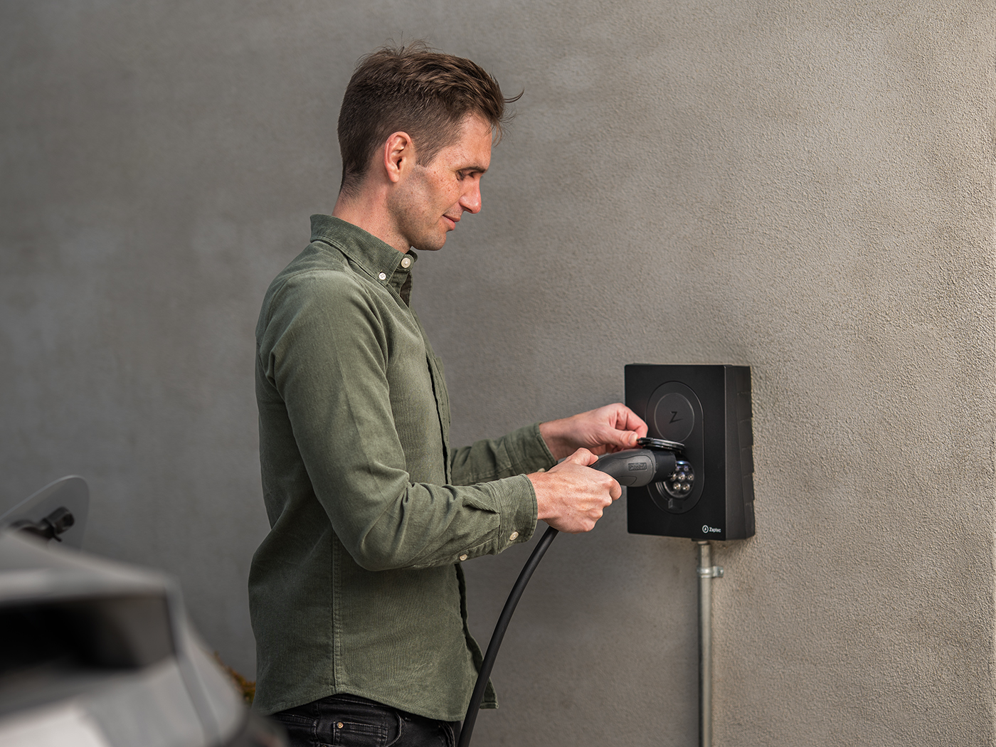 Mand der sætter ladekabel i en ladeboks