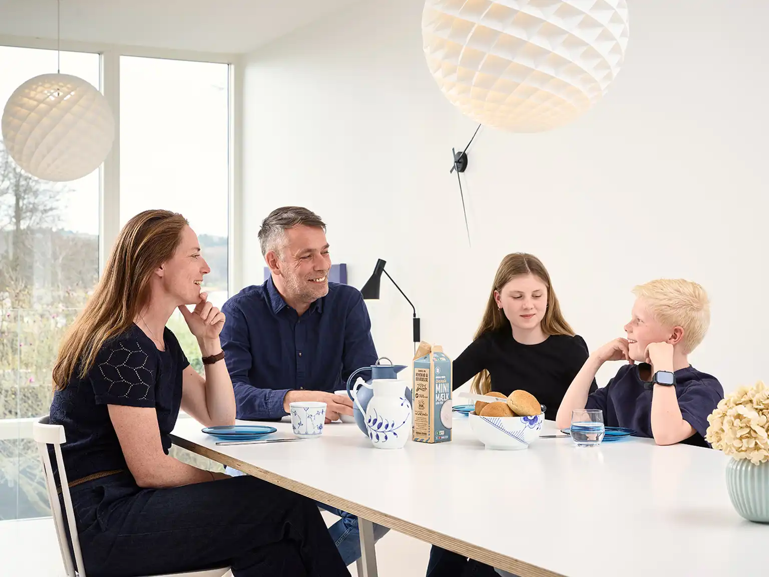 Familie sidder sammen og taler over morgenmaden
