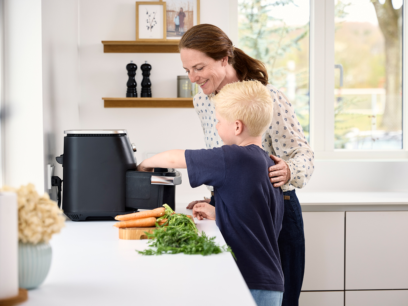 Mor og søn laver mad med airfryer i køkkenet