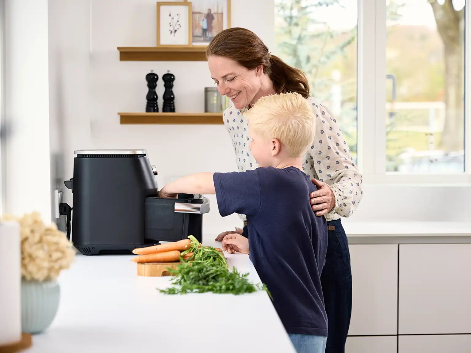 Mor og søn laver mad med airfryer i køkkenet