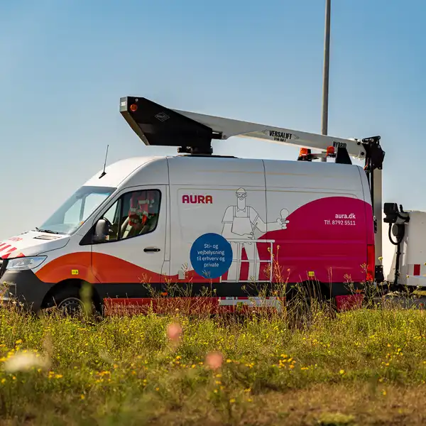 Bil fra AURA Installation holder parkeret ved en markvej nær gadelys
