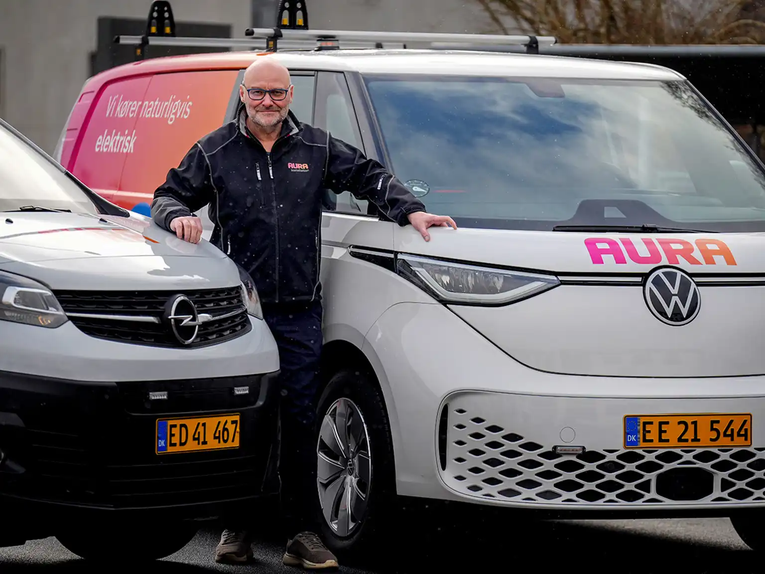 Mand står imellem to installationsbiler fra AURA