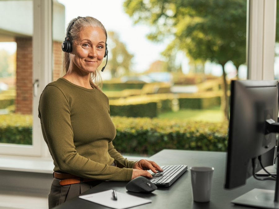 Kvinde med headset står foran en computer