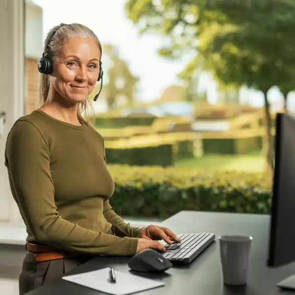 kundeservice-kvinde-med-headset Kvinde med headset står foran en computer